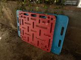 a red and blue plastic pallet laying on the ground