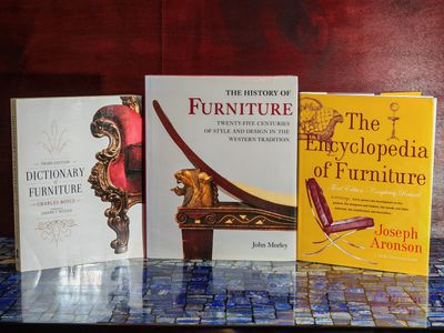 Trois livres sont posés sur une table, devant laquelle se trouve une chaise.