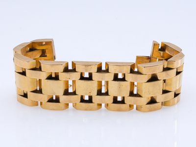 gros plan d'un bracelet en or sur une surface blanche