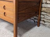 an image of a wooden chest of drawers in front of a brick wall