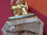une statue en or représentant une femme, posée sur un socle en bois