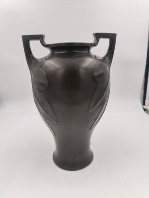 a black vase sitting on a white surface next to a book