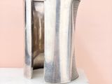 a close up of a silver vase on a white pedestal