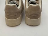 the back of a pair of beige sneakers on a white surface