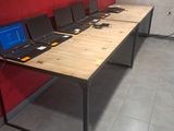 Plusieurs ordinateurs portables sont alignés sur une longue table dans une pièce