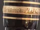 a close up of a wine bottle with a gold band on it