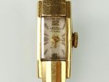 une montre en or accrochée à un mur blanc