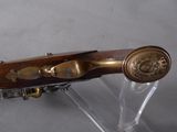 a wooden gun with a brass handle on a clear stand