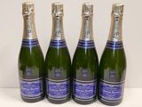 Quatre bouteilles de vin mousseux sont alignées sur une table