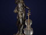 une statue en bronze représentant une femme tenant un violon, posée sur un socle en marbre