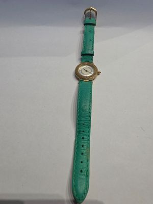 une photo d'une montre verte posée sur une table blanche