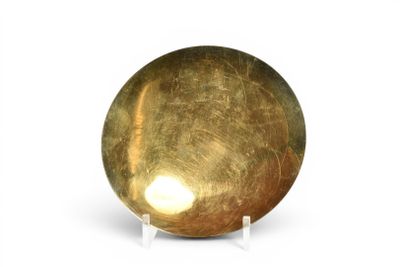 une boule dorée posée sur un socle, sur une surface blanche