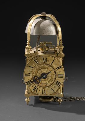 une horloge dorée entourée d'une chaîne, sur fond noir