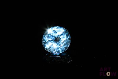 a close up of a blue diamond on a black surface
