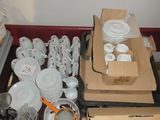 de nombreuses boîtes d'assiettes et de tasses blanches sur la table
