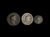 trois pièces romaines, dont l'une représente une tête et l'autre un visage