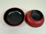 pair of red vases with black lids on a white surface