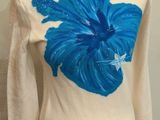 un pull crème orné de fleurs bleues, présenté sur un mannequin