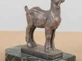statue d'une chèvre posée sur un socle en marbre, elle-même posé sur une table