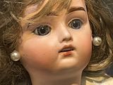 a close up of a doll with a necklace on it