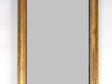un miroir au cadre doré accroché à un mur blanc, à côté d'un autre mur blanc