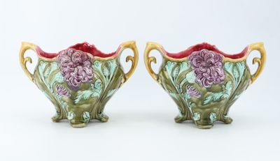 pair of green and pink vases with flowers on them on a white surface