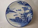 a blue and white plate with a boat on the water