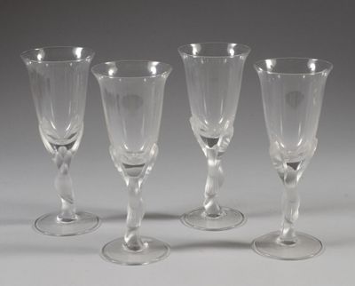 quatre verres à vin vides sont alignés sur une surface blanche