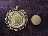 a small coin next to a gold coin on a purple cloth