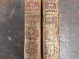 two old books sitting on top of a wooden table next to each other