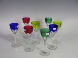 several different colored wine glasses are lined up on a white surface