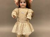 une poupée ancienne en porcelaine représentant une jeune fille vêtue d'une robe et d'un bonnet