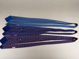 three ties with blue and purple designs on them on a white surface
