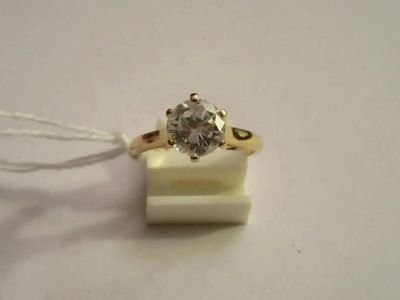 une bague sertie d'un diamant, posée sur un morceau de cire