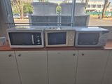 three microwaves sitting on top of a counter in front of a window