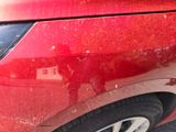 a close up of a red car with scratches on the side of it