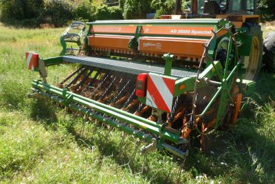 un tracteur immobilisé dans l'herbe, avec une charrue attelée derrière lui