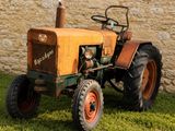 un petit tracteur qui est garé dans l'herbe