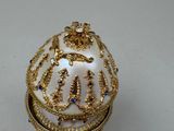 a white egg with gold decorations on it on a table