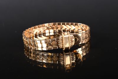 bracelet en or posé sur un fond noir, avec des reflets à la surface