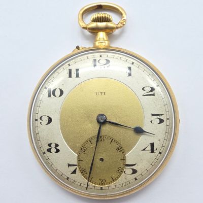 gros plan d'une montre de poche en or sur une surface blanche