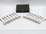 six silver spoons and a box on a white surface