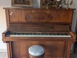 un piano et un tabouret dans une pièce où est accrochée une horloge au mur
