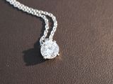 a diamond pendant on a chain on a brown surface