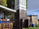 une petite construction en bois avec un toit, située dans un champ herbeux