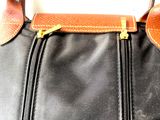 a close up of a black bag with a brown handle