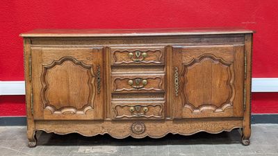 un vieux buffet en bois posé à même le sol, près d'un mur rouge