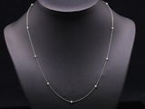 a necklace with pearls on a mannequin with a black background