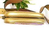 a gold and pink purse with a strap on a white surface