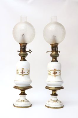 pair of white and gold lamps with glass globes on them
